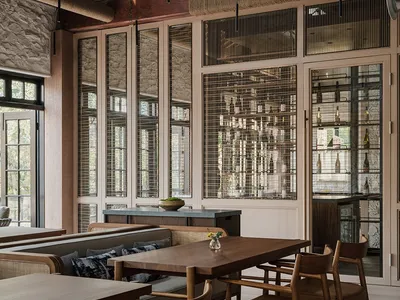Modern restaurant interior with wooden tables, chairs, and exposed wooden beams and rafters.