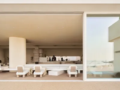 Modern minimalist living room with concrete walls, floor, and furniture.
