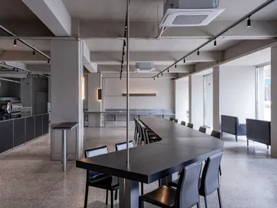 A spacious, modern cafe with a sleek concrete floor, high counter, and long dining table.