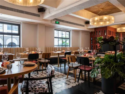 Modernly designed restaurant space with a mix of materials like wooden tables, upholstered chairs, and decorative plants.