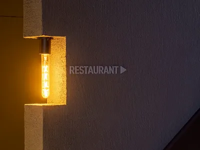 Modern concrete wall with a light bulb and directional sign for a restaurant