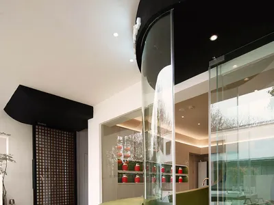 Modern restaurant interior with glass walls and green accents.