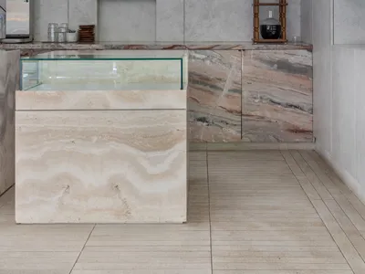A minimalist coffee shop featuring a marble countertop with a coffee machine and a cold-brew coffee stand.