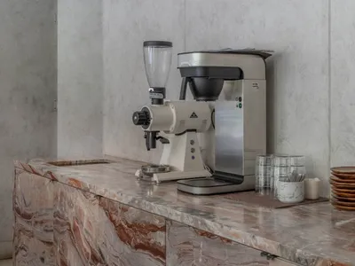 Modern minimalist kitchen with a marble countertop and sleek coffee machine.