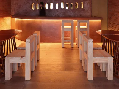 Modern industrial-style restaurant bar featuring textured brick ceiling and wooden stools and tables.