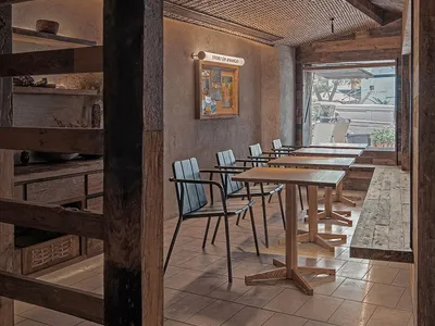 Industrial-style restaurant interior featuring wooden furniture and ceiling beams
