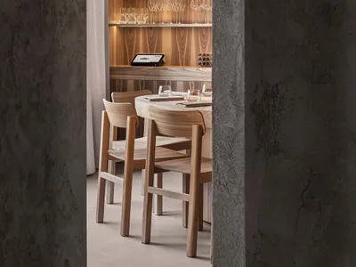 A modern restaurant interior with wooden furniture and shelves displaying wine glasses.