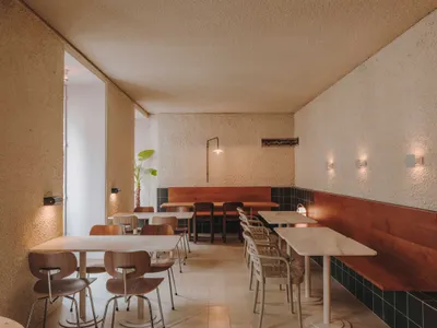 Modern cafe with tables, chairs, and white walls and floors.