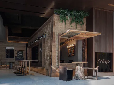 An architectural photograph of an industrial-style restaurant exterior featuring wooden accents, glass windows, and metal ele