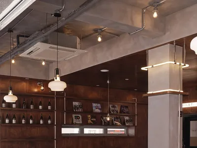 Industrial-style restaurant interior with wooden tables, metal chairs, and concrete walls.
