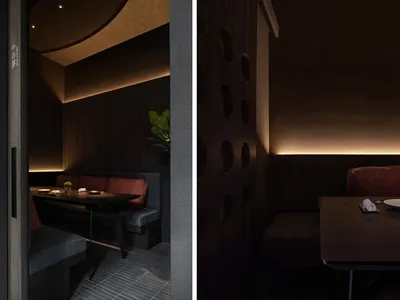 Modern restaurant interior with wood elements and lighting.