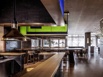 Modern restaurant interior with metal accents, glass walls, and wooden finishes.