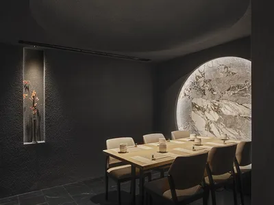 現代簡約餐廳室內，混凝土牆面搭配木質餐桌。