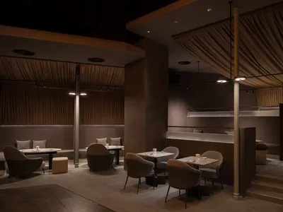 A modern restaurant interior with dark-toned materials and contemporary design elements.