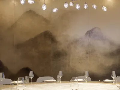 A modern restaurant interior with glass lighting fixtures hanging above a circular dining table with white place settings and