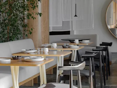 A modern restaurant interior with minimalist design features, including wooden tables, fabric seating, and metallic accents.