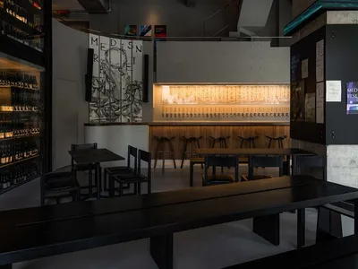 Industrial-themed restaurant interior with concrete bar counter, wooden benches, and minimalist design elements.