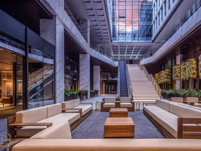 A modern hotel lobby with marble and concrete elements, featuring comfortable seating arrangements and decorative lighting.
