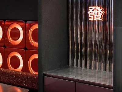 Modern restaurant bar featuring a metallic accent wall with Chinese character lighting.