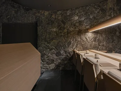 Modern restaurant interior with stone walls and wooden tables and chairs