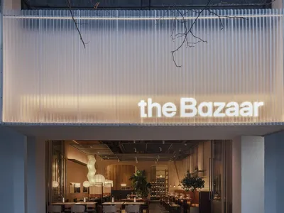 A modern restaurant interior with a illuminated sign reading 'the Bazaar', featuring contemporary design elements and a warm,