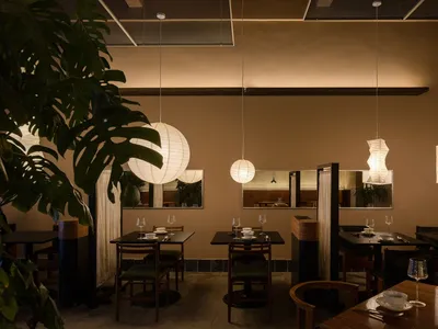 Modern restaurant interior with paper lantern lights, concrete walls, and bamboo accents.