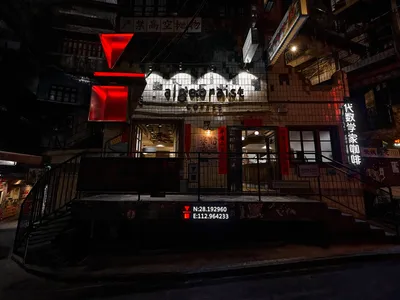 代數家咖啡店夜間外觀，擁有金屬格柵立面，燈光照亮