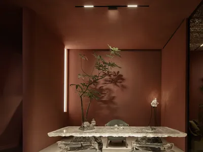 Modern restaurant interior with a glass table, greenery, and minimalist lighting.