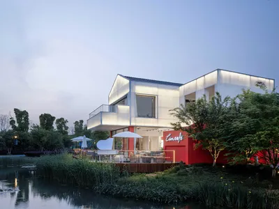 Modern restaurant exterior with white and red surfaces and outdoor seating area.