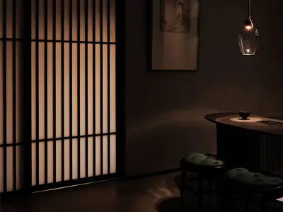A minimalist restaurant interior with dark lighting and wooden materials.