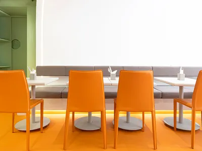 Modern restaurant cafe seating area with orange leather chairs and metal legs