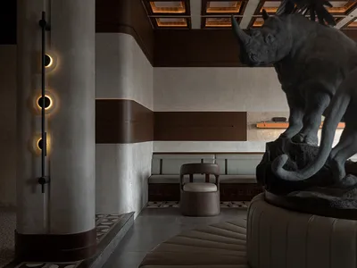 A modern restaurant interior featuring a concrete rhinoceros statue on a circular seating area.