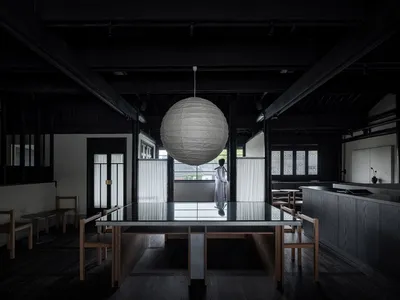 Contemporary restaurant interior with dark wooden furniture and a large spherical light fixture.