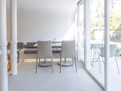 現代簡約餐廳室內，白色牆面、座位與地板，搭配開放式設計與大型窗戶