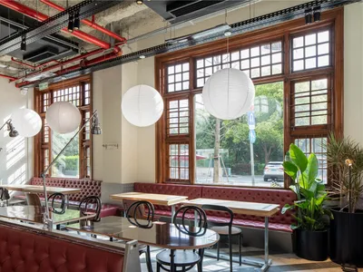 A cozy cafe interior with wooden tables, leather seating, and glass windows