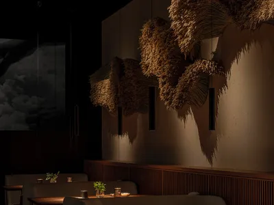 Modern minimalist dining room with wood tables, upholstered benches, fabric and dried-grass accents, and dim lighting.
