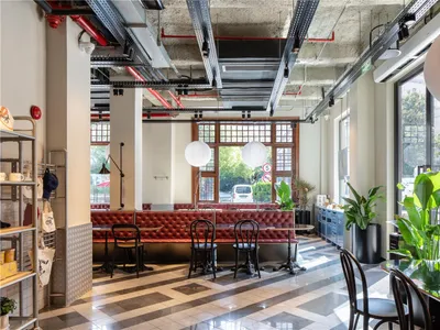An image of a modern cafe interior with concrete walls and wooden tables.