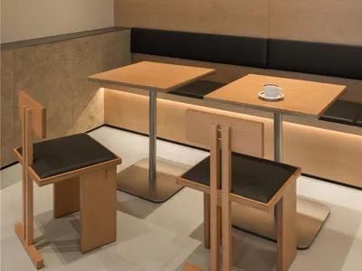 Modern restaurant cafe with wooden furniture, black seats, and square tables with a cup and saucer on one table.