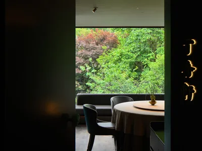A modern, minimalist restaurant interior with a circular table and chairs, illuminated by soft, ambient lighting.