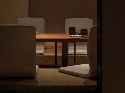 A minimalist restaurant interior with wooden furniture and warm lighting.