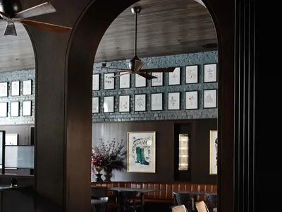 Industrial restaurant interior with brick walls, brown leather booths, wooden tables, and metal accents.