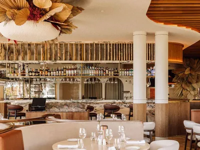 Modern restaurant bar with concrete floor, wood accents, and marble finishes