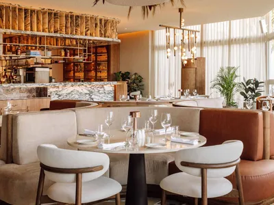 Modern restaurant interior with marble countertops, concrete floors, and wooden furniture.