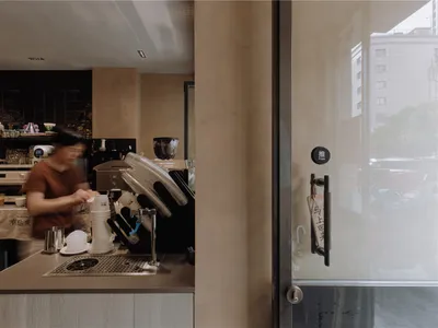A clean, minimalist coffee shop counter made of metal, with a person preparing a drink.