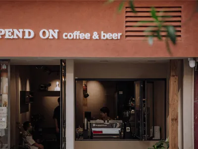 紅土泥牆的店面，招牌寫著「DEPEND ON coffee & beer」。