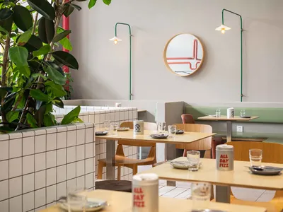 Modern cafe interior featuring tile and wood materials with greenery and stylish lighting.