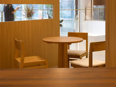 Modern restaurant interior with wooden furniture and glass walls.