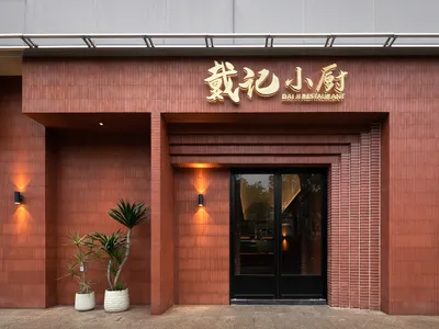 A brick restaurant exterior with a black door and gold lettering.