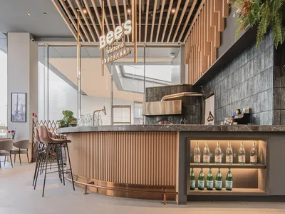 Modern cafe bar interior with wooden slat ceiling, marble countertop, and glass bottles.