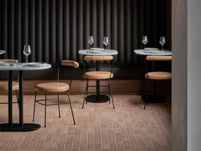 Modern dining room with metal tables, leather chairs, and wooden walls.